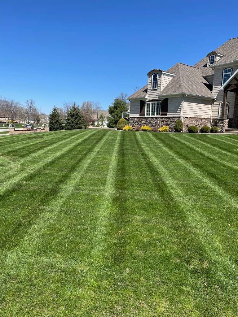 Manicured Ohio backyard with stone patio, retaining wall and lush lawn at golden hour